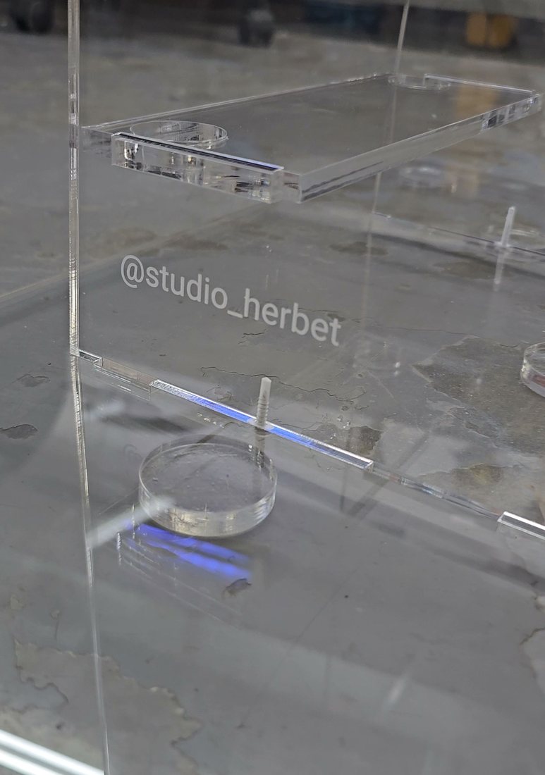 הלוגו @studio_herbet חרוט בלוח השקוף, בסדנה