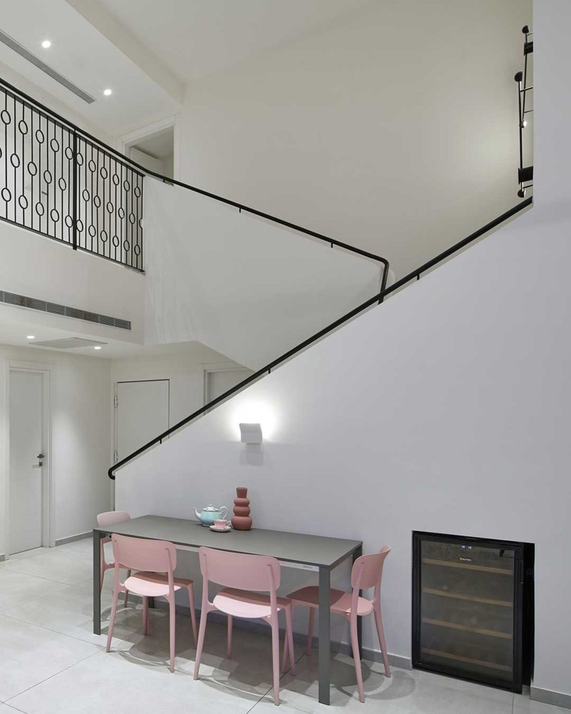 The staircase from the dining area: the black handrail climbs along the wall and continues to the circle railing on the second floor